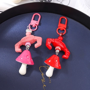 Charming mushroom keychain pendants in pink and red with beads on dark blue tray