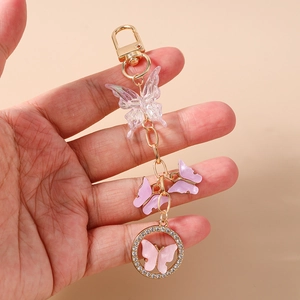 Detailed close-up of a pink rhinestone butterfly keychain held by hand in a warm light
