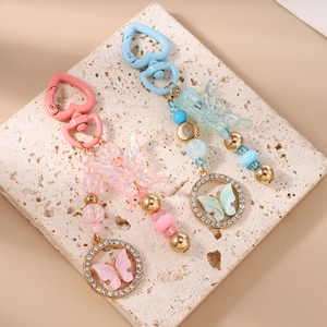 Détails de porte-clés papillon à perles roses et bleues sur pierre beige