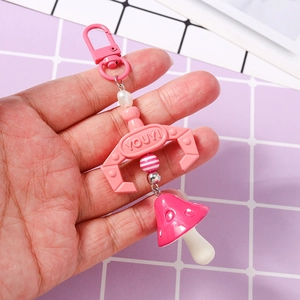 Detailed view of pink mushroom keychain with mechanical claw and striped bead accessories