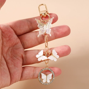 Detail of a golden butterfly keychain featuring iridescent charms and rhinestone ring