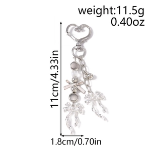Détail d'un porte-clés perlé argenté avec fermoir coeur, pendentif nœud et petite clochette