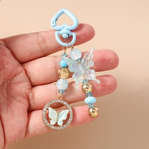 Détail du fermoir en forme de cœur bleu clair et du porte-clés papillon perlé avec strass