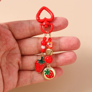 Detail of red heart-shaped clasp with strawberry charms and beaded keychain for bags