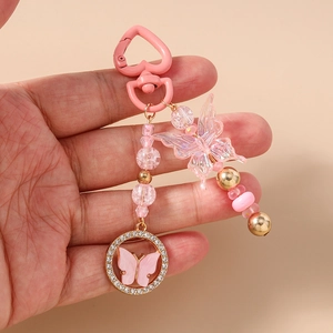 Détail d'un porte-clés rose perlé avec fermoir en cœur et pendentif papillon strass