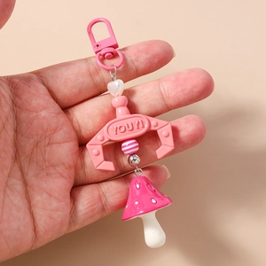 Pink heart bead keychain with metal claw charm and mushroom pendant held in hand