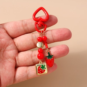 Detail of beaded strawberry keychain with red heart carabiner and gold enamel pendant