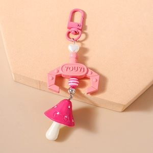 Detail of pink keychain with lobster clasp, pearl heart and red mushroom charm on a stand
