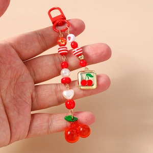 Macro shot of handcrafted cherry beaded keychain with red metal ring and gold charm