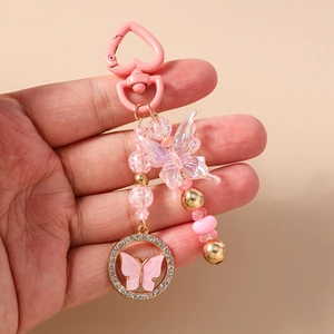 Détail d'un porte-clés papillon rose avec des charmes en cristal et des perles