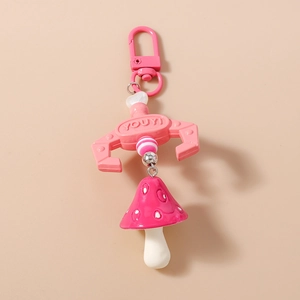 Detailed view of a pink claw machine keychain with a red polka dot mushroom pendant
