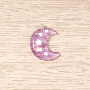 Primer plano de colgantes de luna violeta translúcida con lentejuelas de estrellas