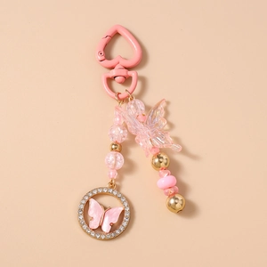Détail d'un porte-clés papillon rose avec perles acryliques et anneau strass