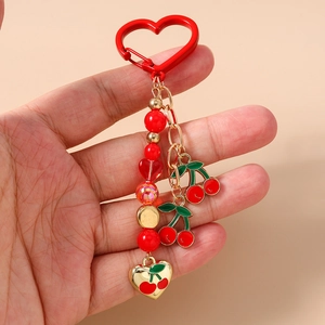 Detail of beaded cherry keychain featuring red heart beads and enamel fruit charms