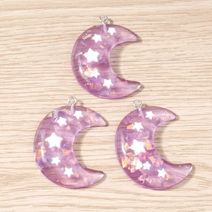 Detalle de dijes de luna de resina violeta con estrellas para bisutería DIY