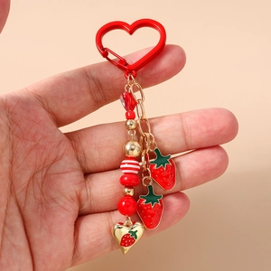 Detailed view of red strawberry beaded keychain with gold heart clasp and charms