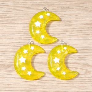 Detalle de colgantes de luna de resina amarilla con estrellas para bisutería DIY