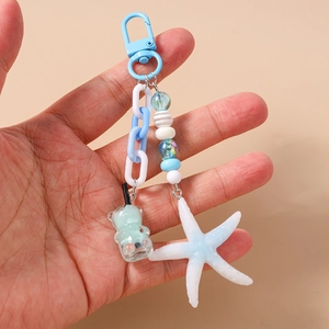 Detail of ocean-themed keychain with blue starfish, bear-shaped drink charm, and beads