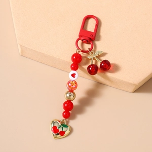 Detailed view of red cherry keychain with beaded charms and metallic lobster clasp