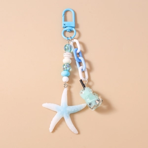 Close-up of blue starfish and gummy bear drink pendant keychain for bags