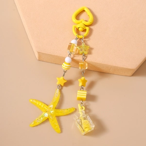 Detailed macro view of yellow starfish pendant and drink bottle charm for keychain decor