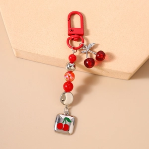 Detailed view of cherry keychain featuring red beads and resin pendants on stone base