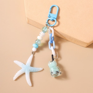 Detail of ocean-themed keychain with starfish and bubble tea charms on apricot background