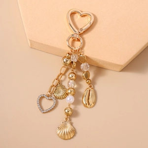 Detail eines goldenen Herz-Schlüsselanhängers mit Strass, Muscheln und edlen Perlen