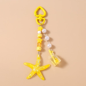 Detail of yellow starfish pendant keychain with star beads and mini bottle charm