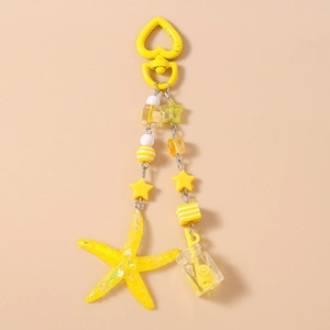 Detail of yellow ocean-themed keychain featuring starfish, lemon bottle, and beads