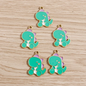 Five green cartoon dinosaur charms with gold metal edges and purple details for jewelry making