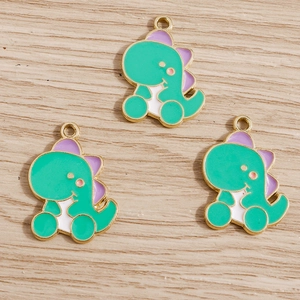 Detailed macro view of three green dinosaur charms with gold plating and enamel finish