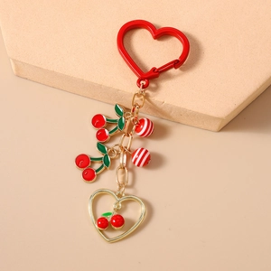 Detailed close-up of a handmade cherry beaded keychain with red heart clasp and enamel charm