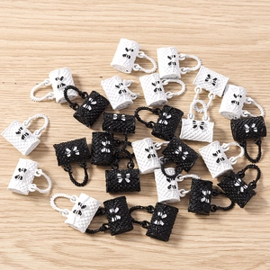 Detailed view of quilted handbag charms with bows in black and white colors