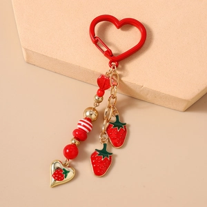 Detailed strawberry charm keychain with red heart carabiner and enamel pendants on pink base