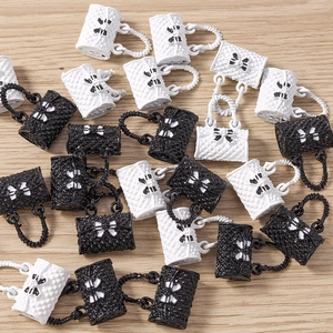Close-up of mini quilted handbag charms with bows for DIY jewelry on wooden background
