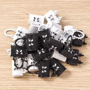 Detailed close-up of quilted handbag pendants with bow accents in black and white colors