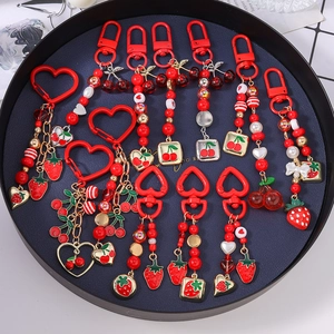 Beaded keychain set featuring red strawberry, cherry and heart pendants on a metal tray