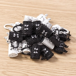 Close-up of quilted handbag charms with bow details in black and white finish