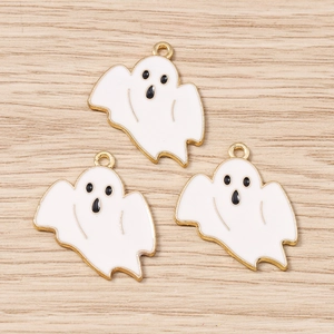 Détail de trois pendentifs fantômes en émail blanc avec bords dorés sur fond de bois