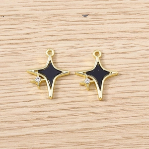Détail de cinq pendentifs étoiles avec émail noir et cristaux sur fond de bois