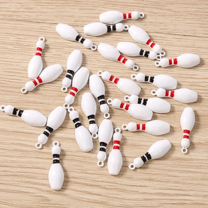 Détail de breloques en forme de quilles de bowling blanches pour la création de bijoux DIY
