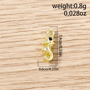 Détail macro d'un pendentif hippocampe doré, dimensions 1,4 cm par 0,6 cm et 0,8 g