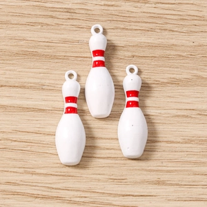 Détail de trois pendentifs de bowling blancs avec bandes rouges pour la création de bijoux