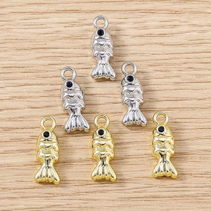 Vue macro de 6 pendentifs poissons or et argent avec écailles 3D sur fond de bois