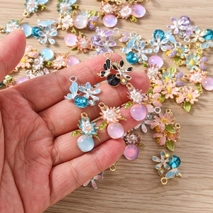 Détail de breloques fleurs et papillons faits main avec émail et perles nacrées