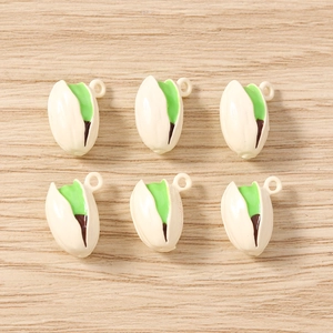 Set of realistic pistachio nut charms for DIY jewelry making on wooden background