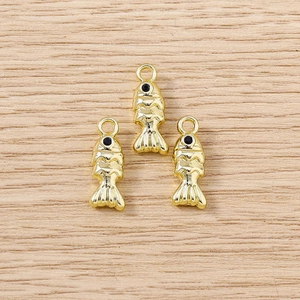 Détail de trois pendentifs poissons dorés avec yeux en strass noirs sur bois