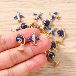 Detailed close-up of airplane and globe enamel pendants for DIY jewelry making