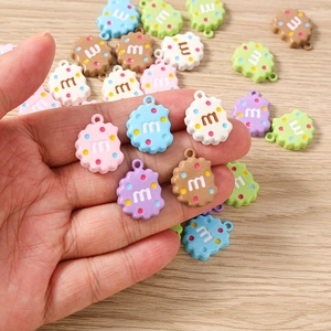 Gros plan de pendentifs cookies en résine colorée avec lettre m pour bijoux DIY sur bois